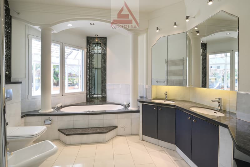 large bathtub, double sink, two toilets, large mirror, white tiles, white walls