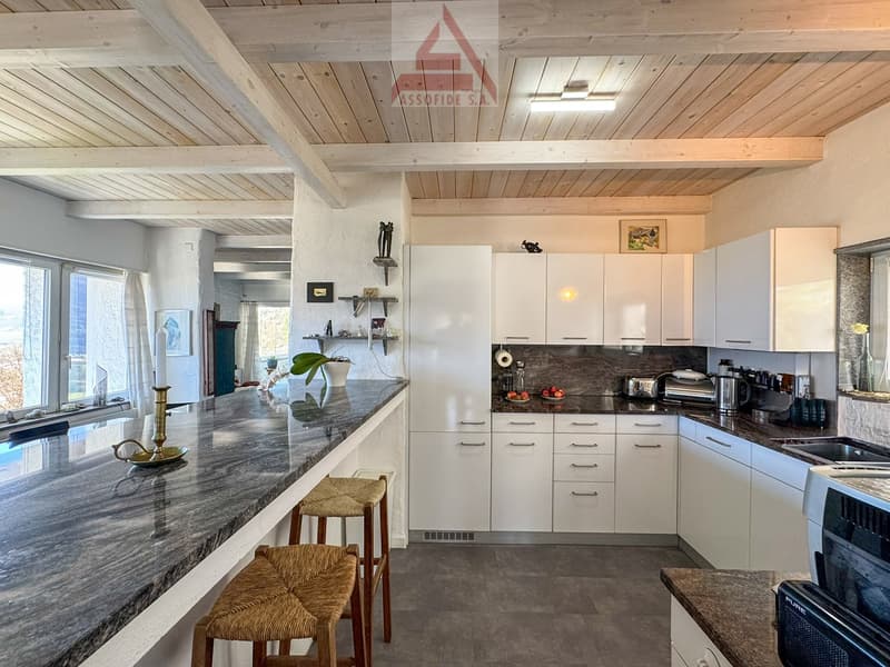 modern kitchen with granite countertops, white cabinets, wooden beams, large windows, bar stools, various kitchen appliances