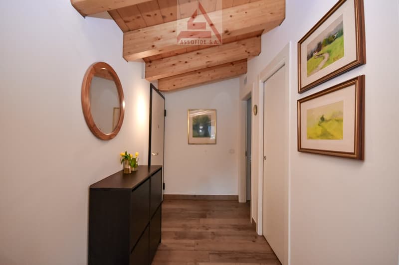 wooden ceiling, wooden floor, white walls, round mirror, wooden cabinet, two framed paintings