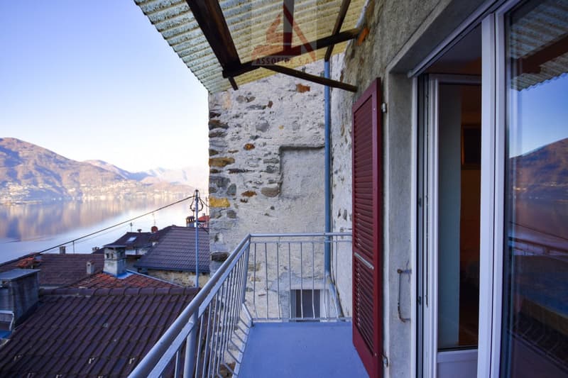 Balcony with metal railing, red shutters, view of mountains and lake