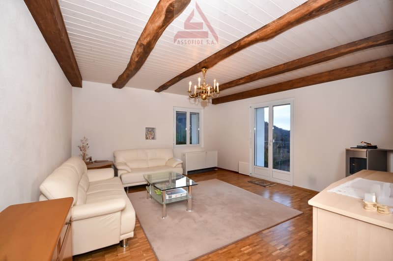 living room with white leather couches, glass coffee table, wooden floor, wooden beams, chandelier, windows, radiator, rug