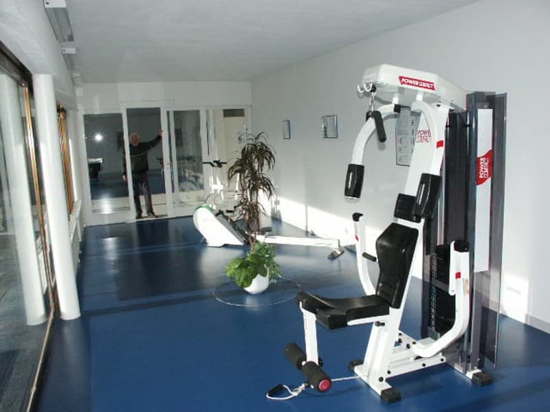 Fitness equipment, potted plant, person in doorway, sliding glass doors, bright lighting