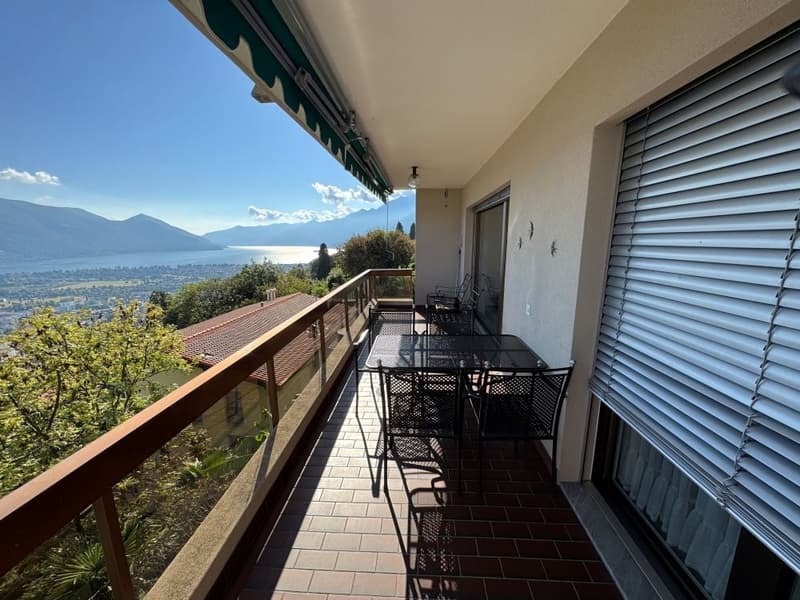 Outdoor dining area, wooden railing, tiled floor, chairs, table, lake view, shade from awning