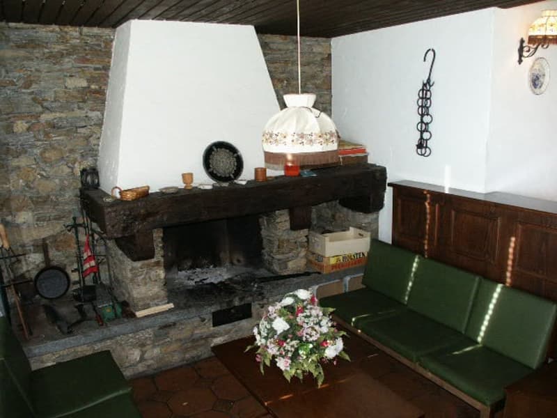 stone fireplace, green sofas, flower arrangement on table, hanging lamp, wall sconce