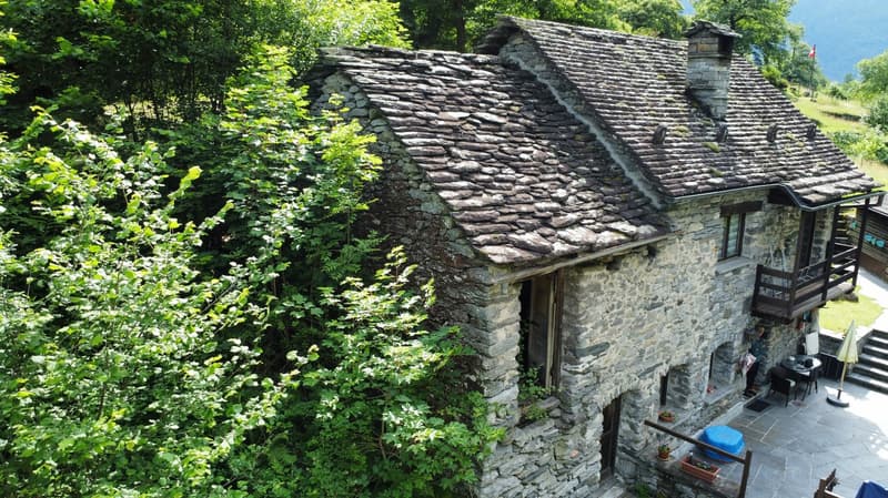 Stone house, slate roof, wooden balcony, surrounded by greenery