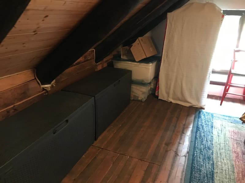 attic room with wooden floor, wooden ceiling, storage boxes, storage boxes with wheels, storage box with lid, storage box with cover, window, red chair