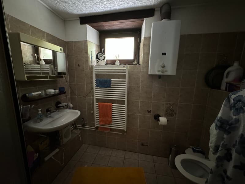 Bathroom with sink, toilet, towel rack, and window