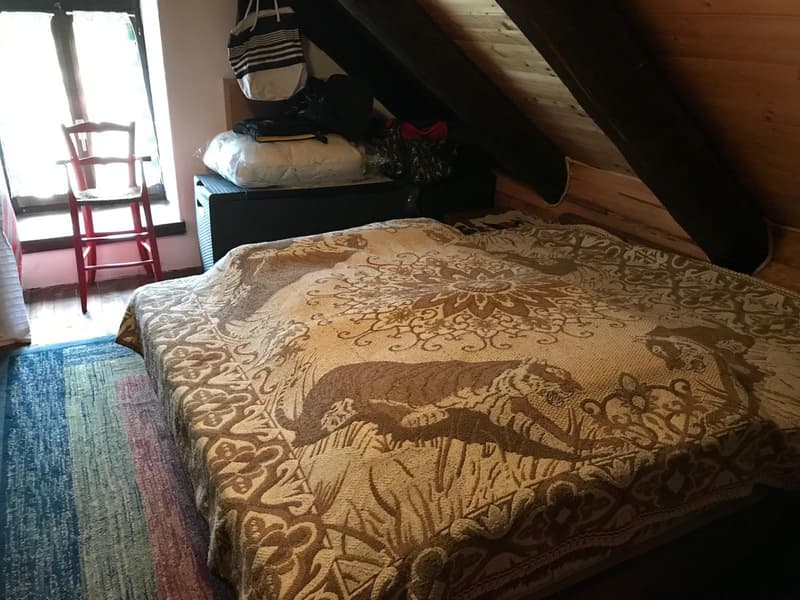 bedroom with bed, wooden ceiling, window, chair, rug, storage boxes
