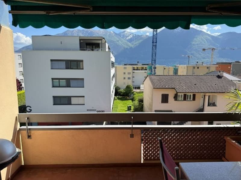 Balcony with metal railing, table, chair, and a view of the mountains