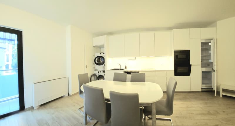 white kitchen with modern appliances and dining table, washing machine in a corner