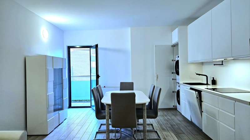 Dining area with dining table and chairs, white cabinets, kitchen with sink and dishwasher, private washing machine, door leading to balcony