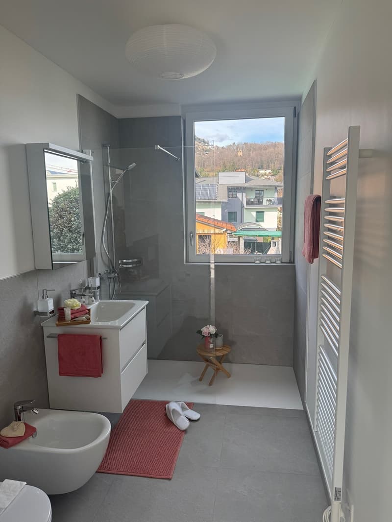 modern shower, window, vanity with sink, mirror, and towel rack, toilet, towels and slippers, floor heating, decorative flowers