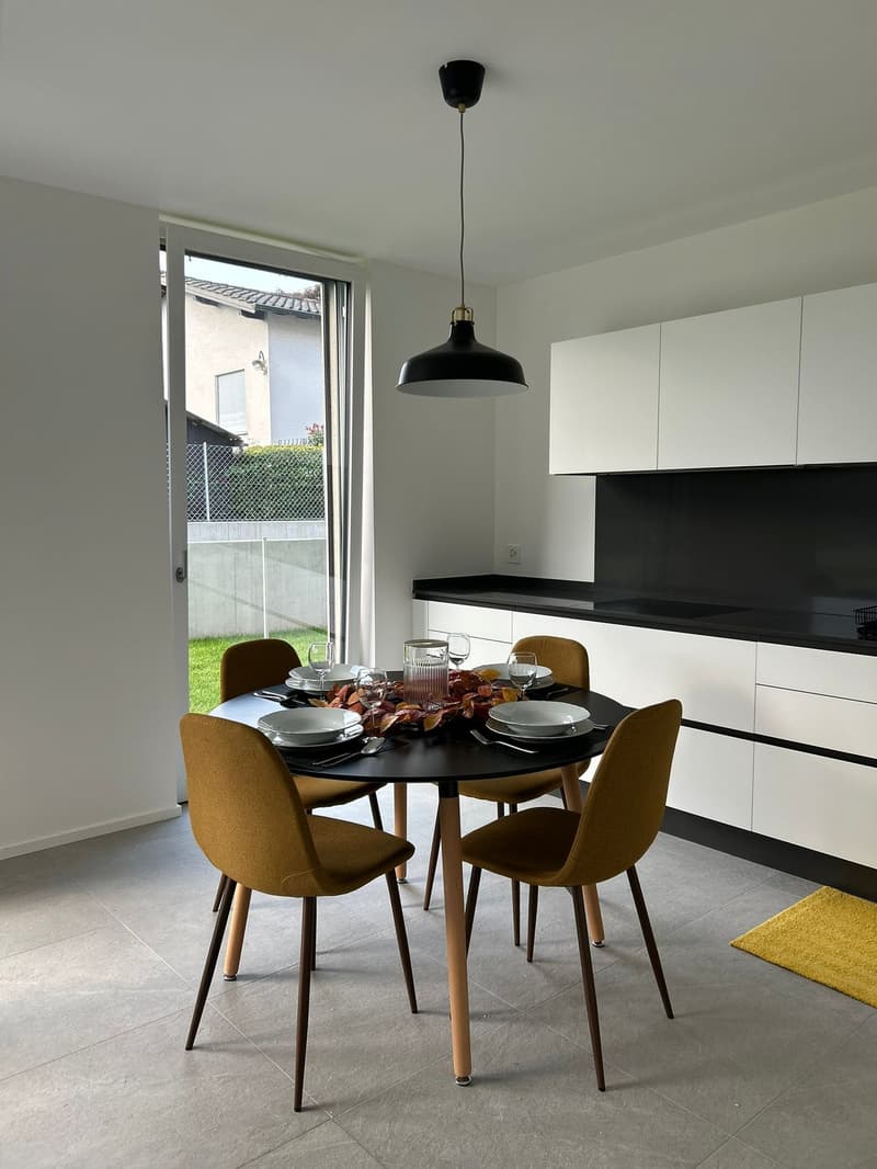 modern dining area with 4 chairs, round table, overhead lamp, glass window, sliding door, floor to ceiling cabinets, counter, sink