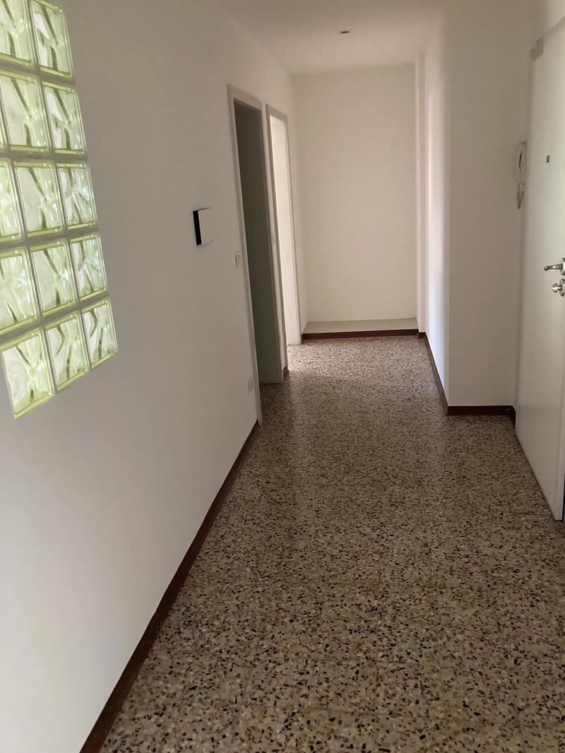 Empty room, granite flooring, white walls, two doors, power outlets, glass panel wall
