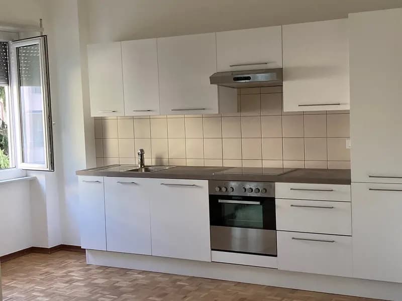 white kitchen with tiled walls, stainless steel appliances, white cabinets and countertops, double basin sink with a faucet, range hood above stove