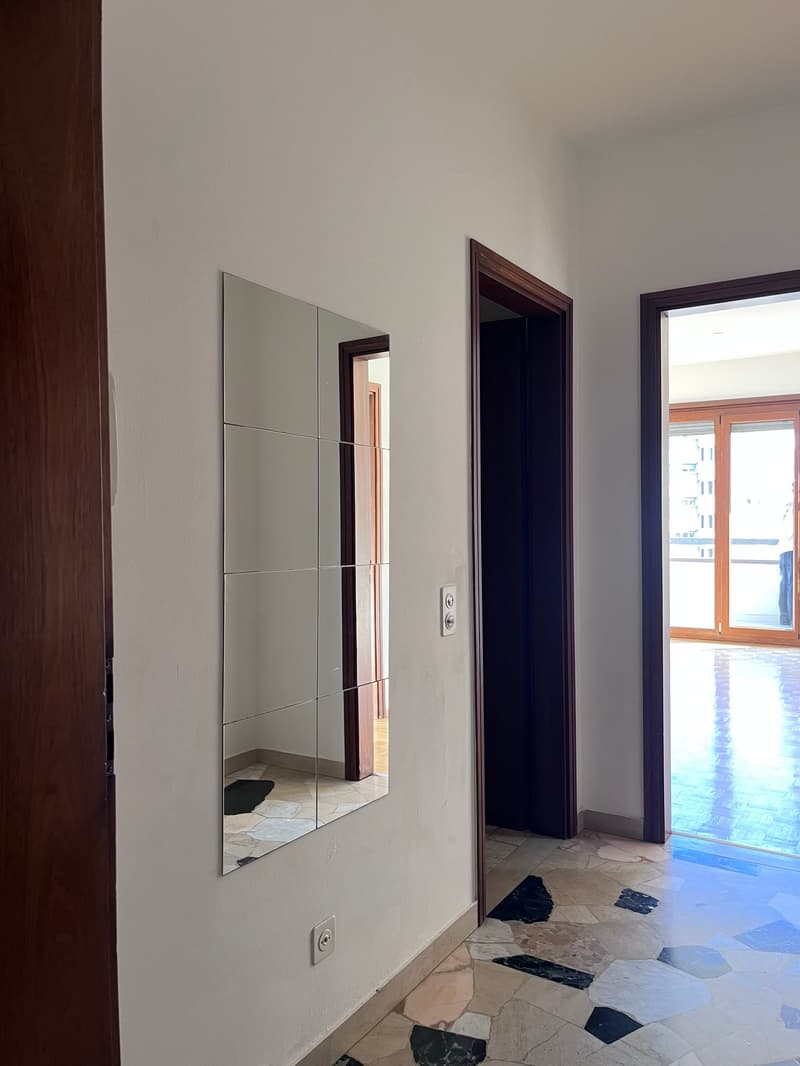 Empty room with white walls, mirror, and tiled floor.