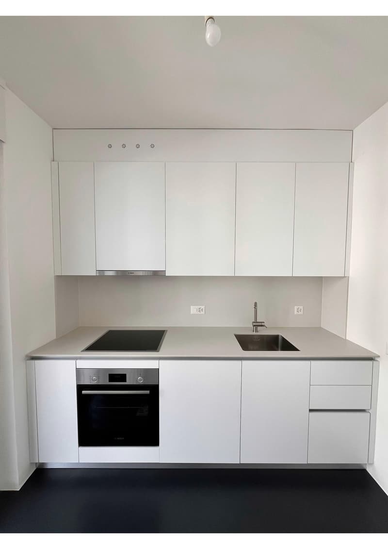 modern kitchen with white cabinets, black floor, induction stove, oven, sink, faucet, power outlets