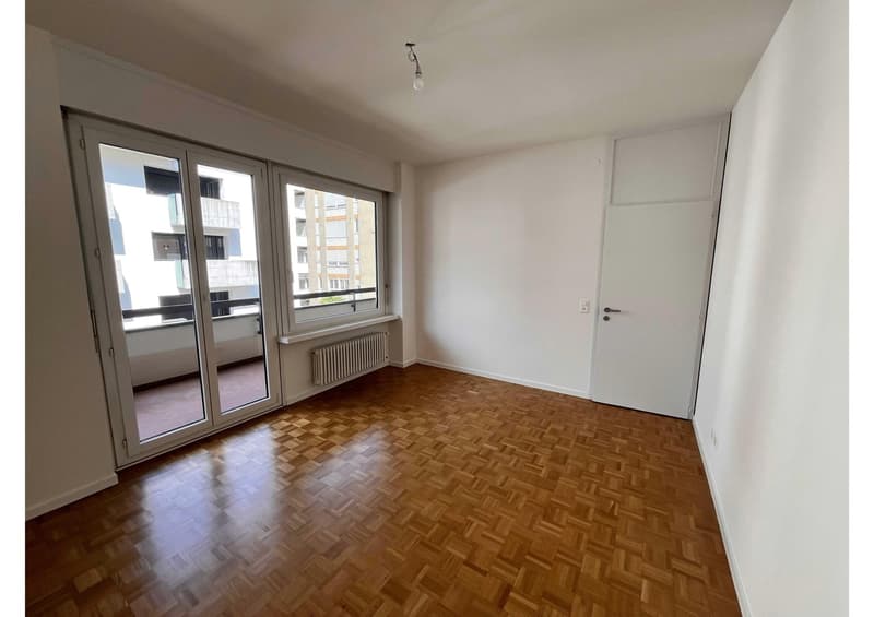 empty room, wooden parquet floor, sliding glass doors, balcony, white walls, white door, radiator