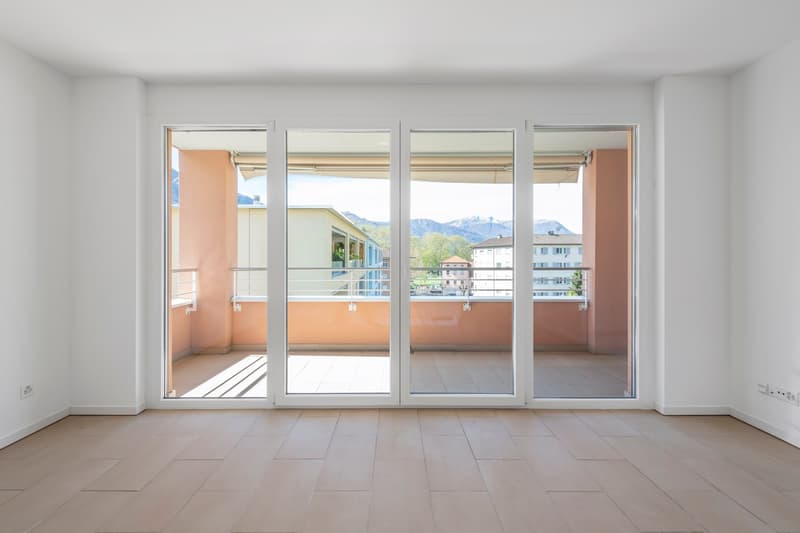 room with large glass doors leading to a balcony, with a view of the mountains