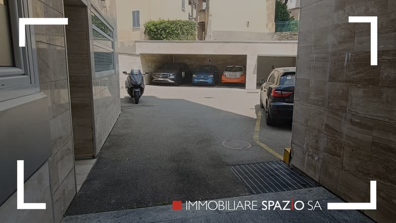 garage parking area with four cars parked and a motorbike on the entrance