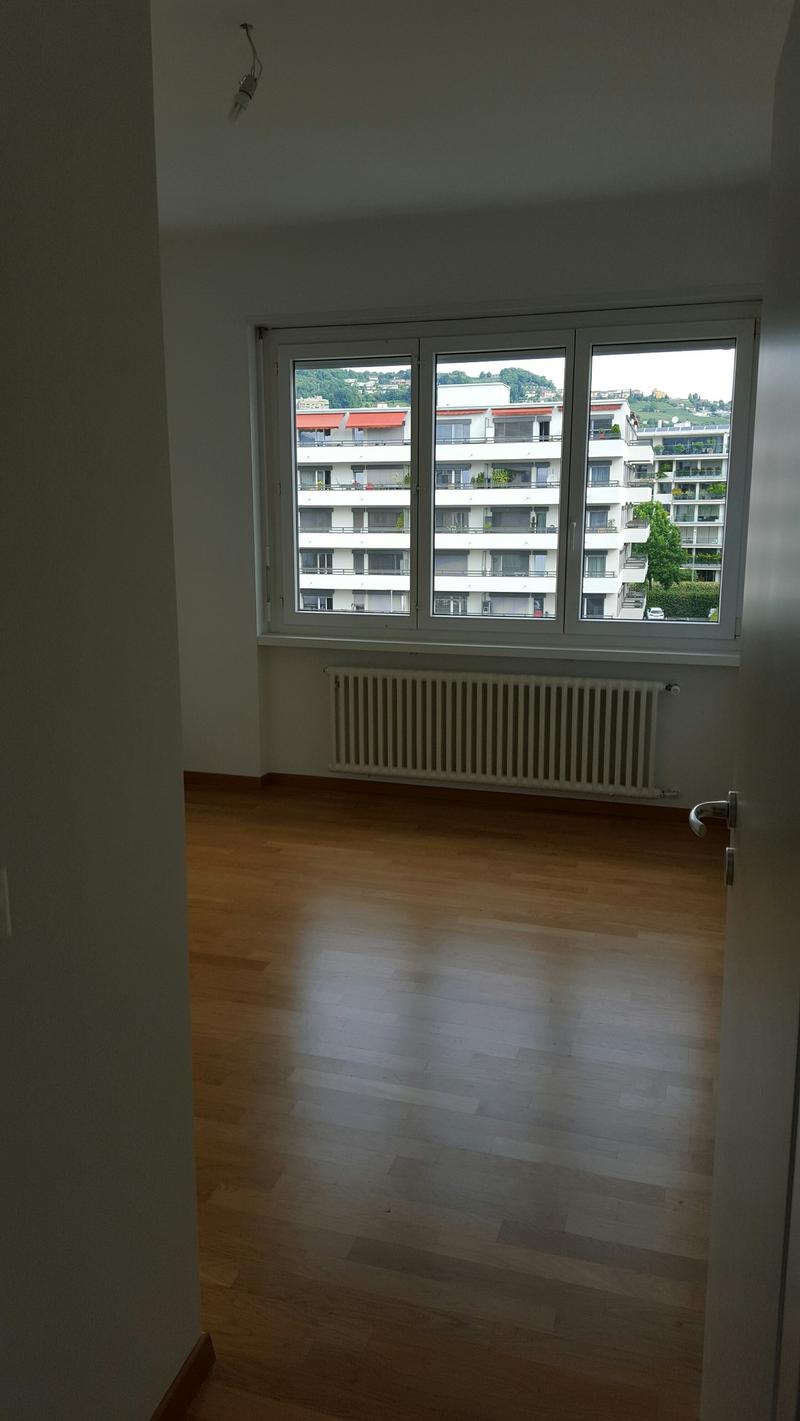 empty room with hardwood floor, large windows, white walls, radiator, outdoor view