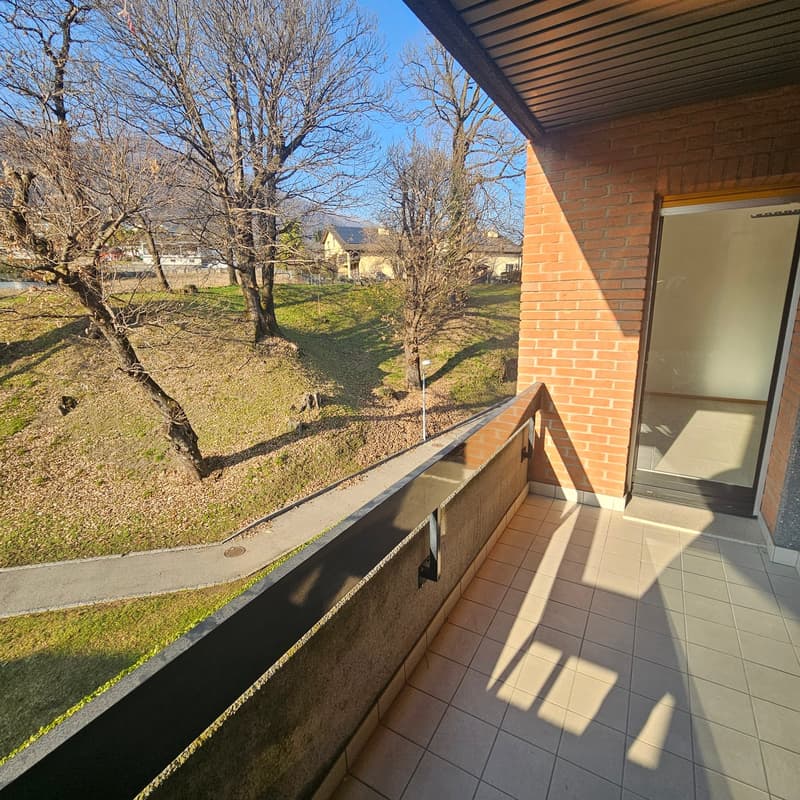 Open balcony with tiles and trees in background, view of grass and mountains