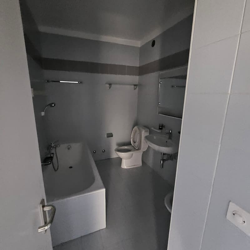 Bathroom with toilet, bathtub, sink, and mirror, all in white