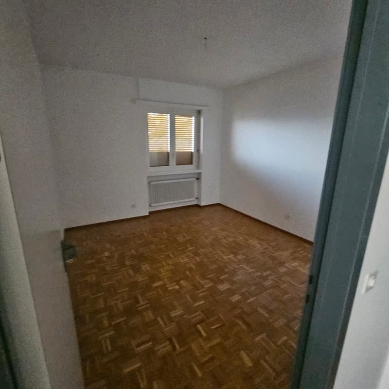 empty room, white walls, wooden floor, white radiator, window with wooden shutters