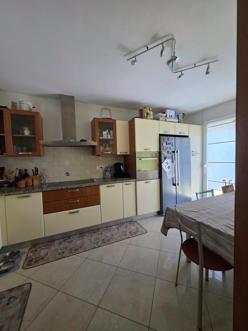 modern kitchen with white cabinets, granite countertops, stainless steel appliances, and a dining area with a table and chairs