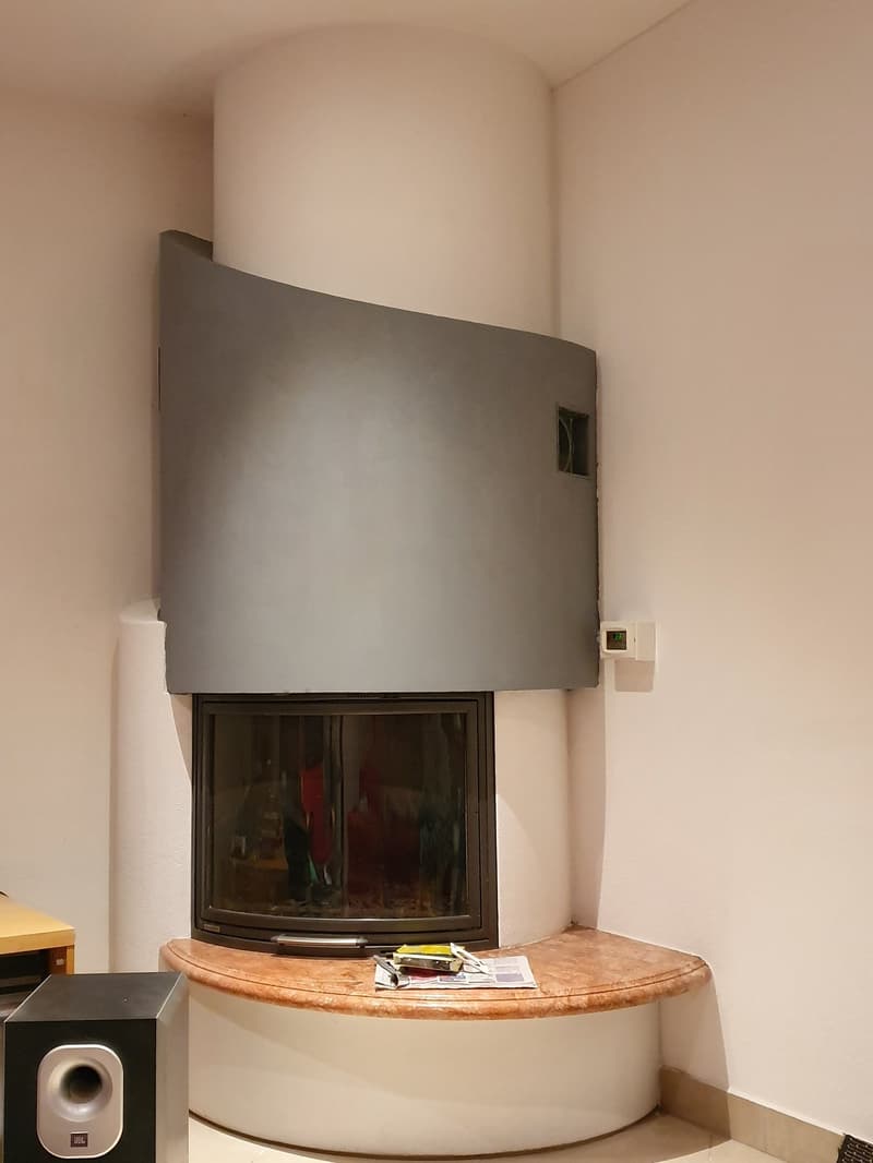 Corner fireplace with a curved mantle, glass doors, and a marble bench