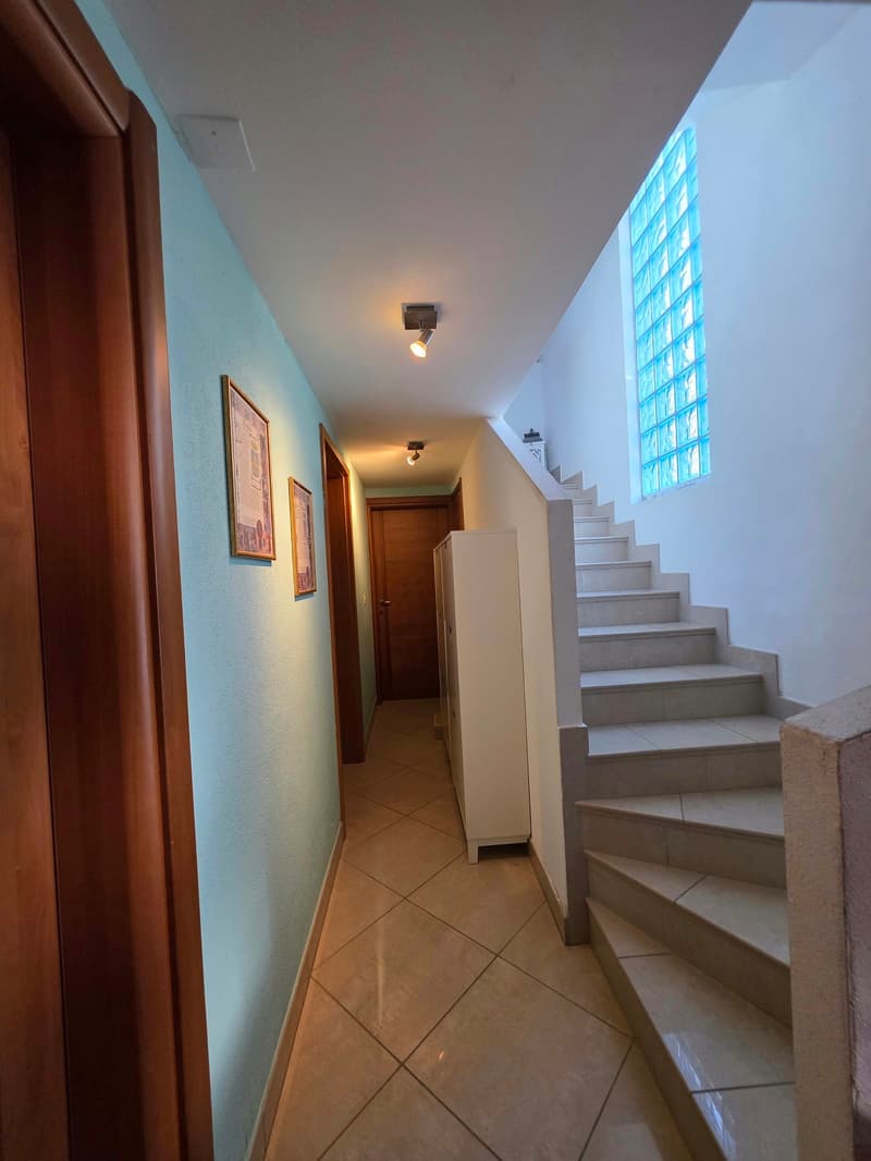 tiled floor, blue walls, wooden doors, white cabinet, staircase, ceiling lights