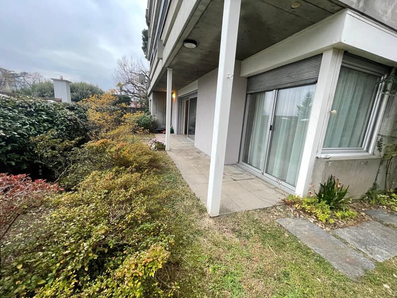 white exterior, concrete patio, glass doors, hedges