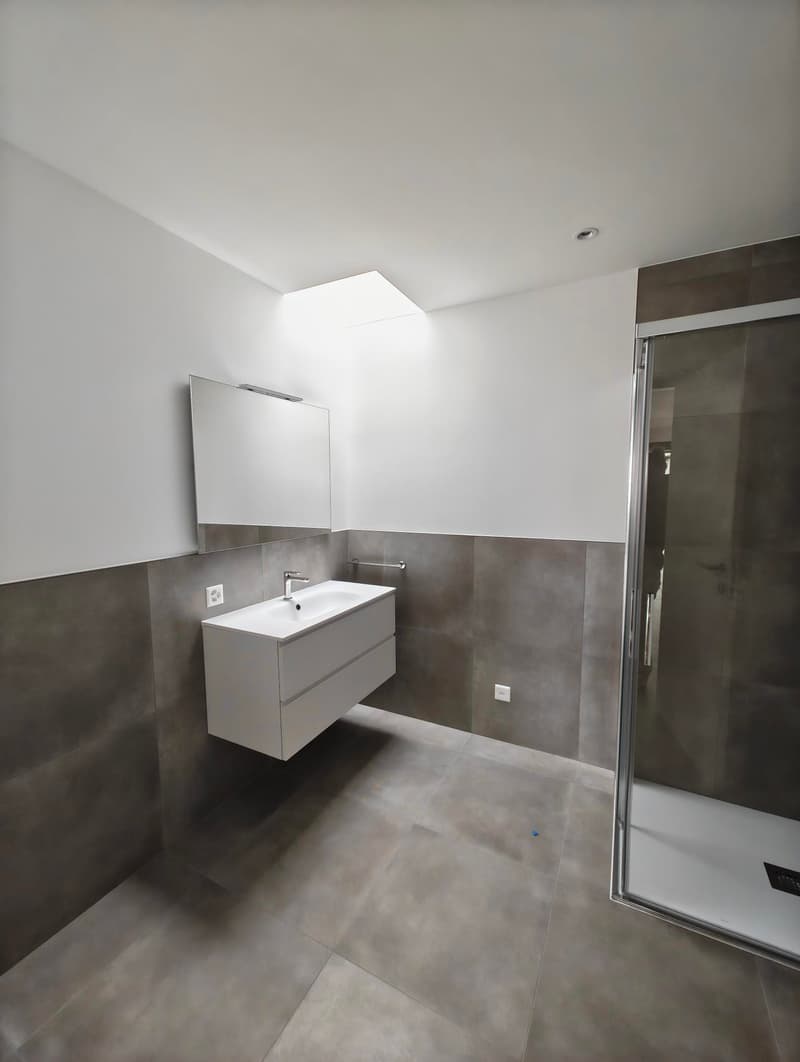 modern style bathroom, white tiled wall and floor, glass walk-in shower, white sink and mirror, towel rack