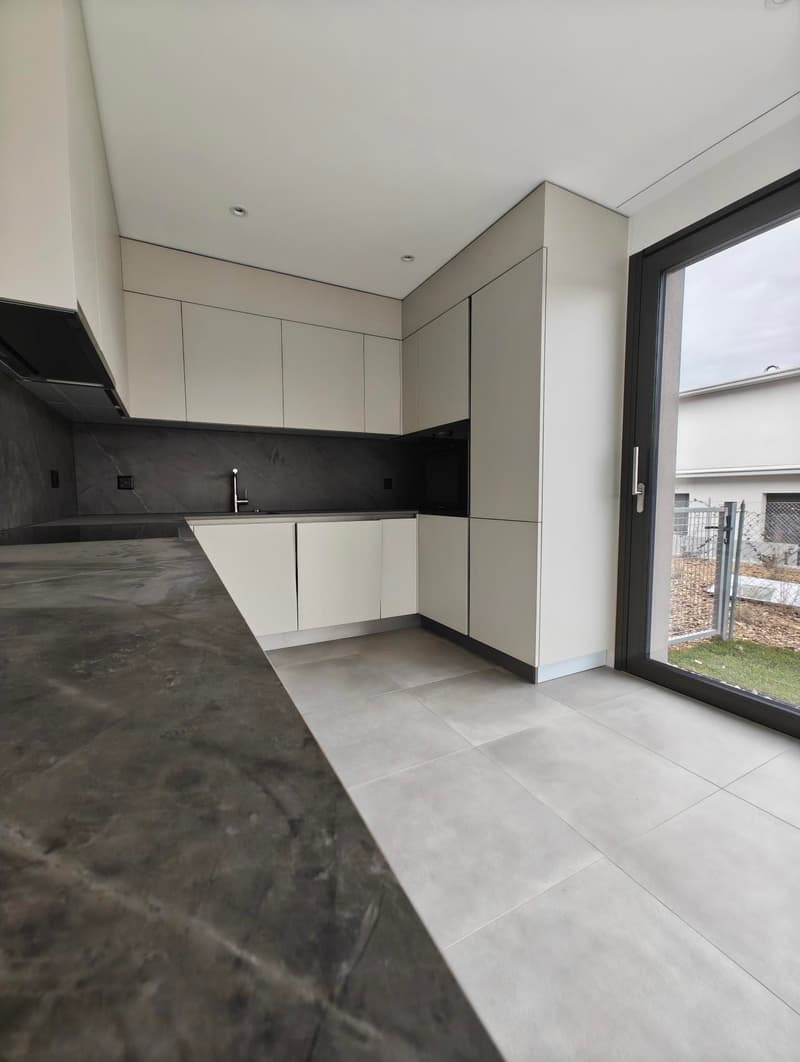 Modern kitchen with white cabinetry, granite countertop, stainless steel faucet, integrated oven, glass door