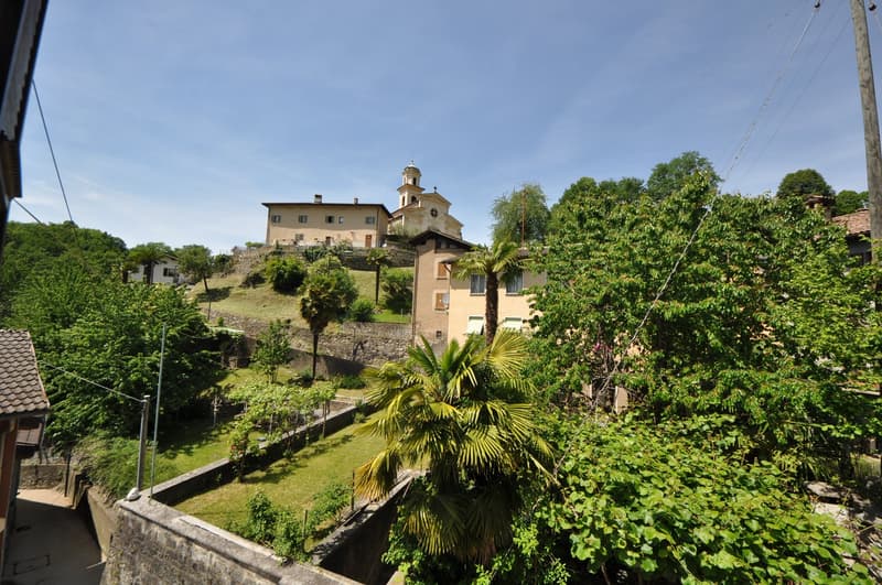 House on hill, several buildings, surrounded by trees, well-maintained garden, clear view