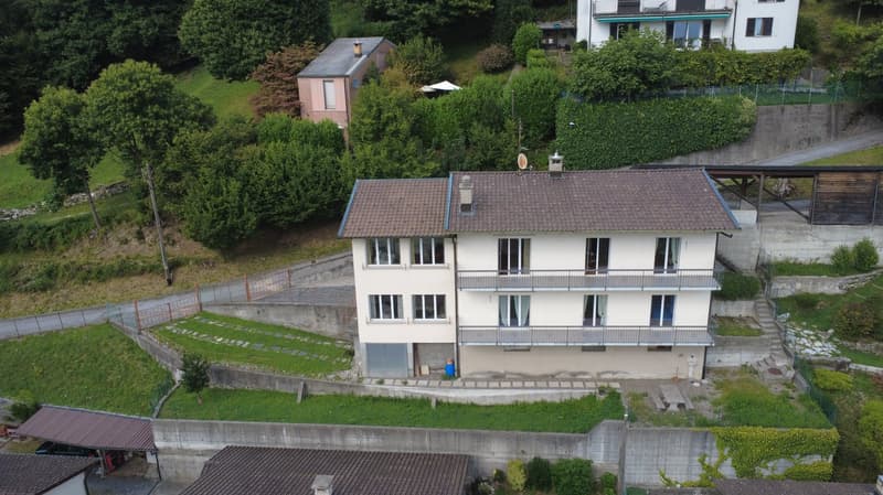 2 story house, brown roof, white walls, balcony on second floor, green grass, concrete walls, car parked under cover