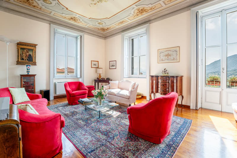red velvet armchairs, glass coffee table, floral vase, wooden floor, chandelier