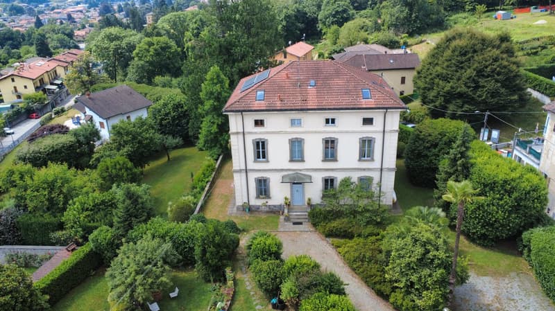 2 story house, brown roof, large windows, central door, multiple balconies, garden, path, trees