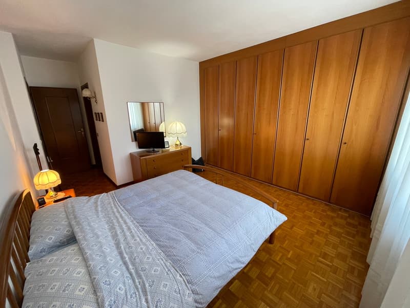Double bed, wooden headboard, night tables with lamps, wooden dresser with TV, mirror, wooden wardrobes, parquet floor, curtains