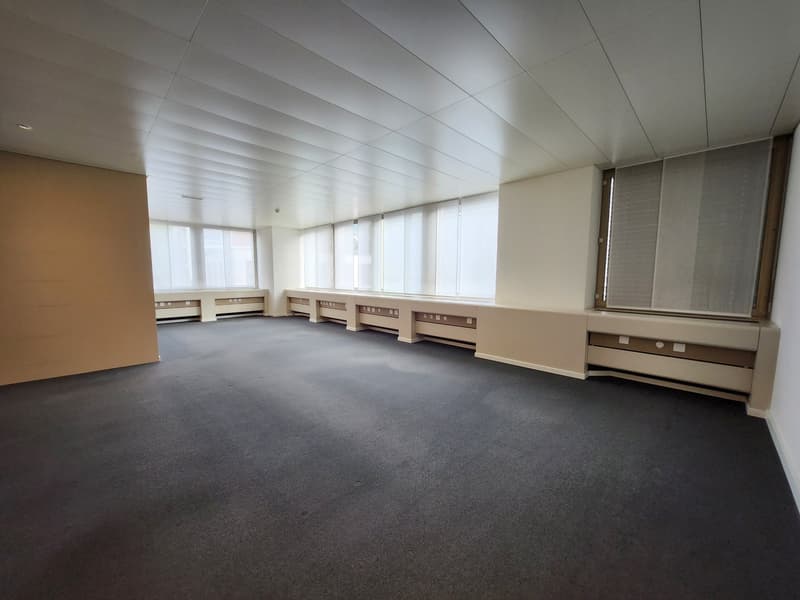 empty room with white walls, black carpet, three long windows, air conditioning units