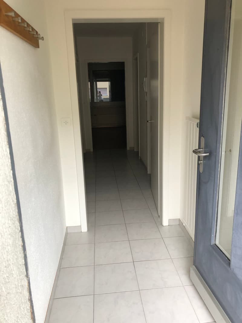White tiled floor, white walls, open doors leading to other rooms