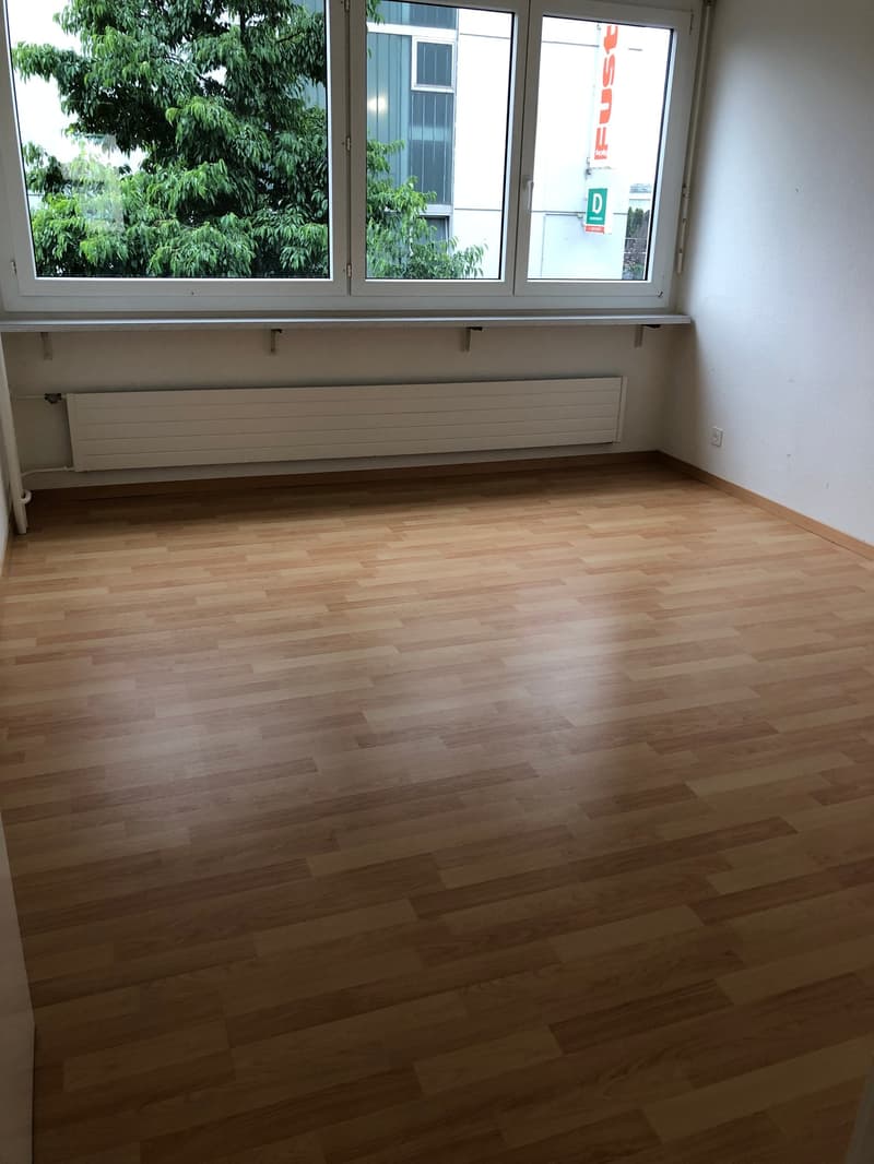empty room, wooden floors, large windows with views of trees