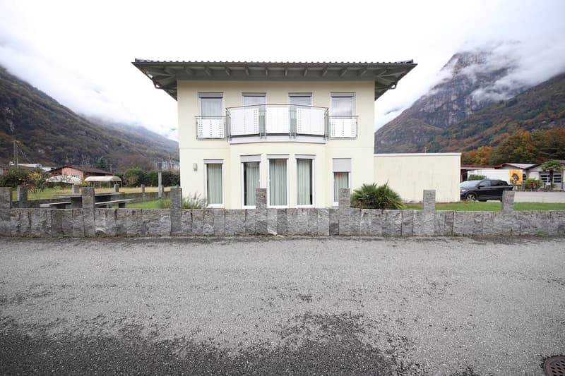 Two-story house, white exterior, balcony, gray gravel driveway, mountain view, white windows, large front yard