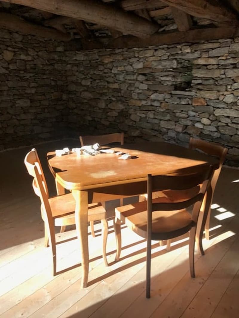 Rustic wooden table and chairs in a room with stone walls and a wooden ceiling
