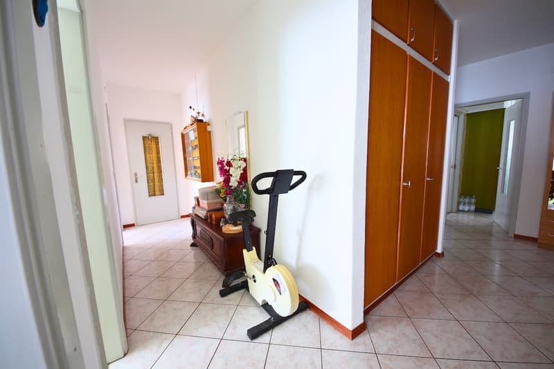 exercise bike, wooden cupboards, mirror, white tiles, vase with flowers