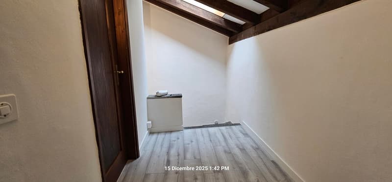 Empty room with a wooden door, wooden beam ceiling, a wooden floor and white walls.