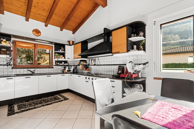 modern kitchen with white cabinets, black countertops, tiled floor, large window, dining table, chairs, appliances