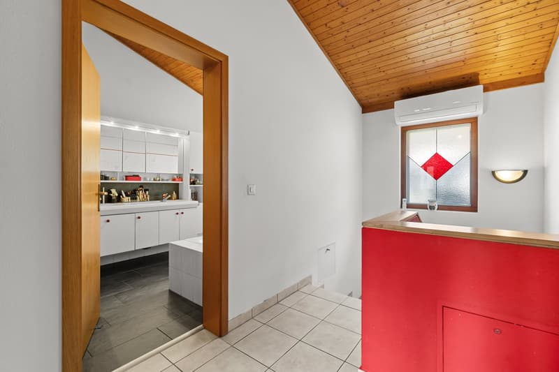 modern kitchen with white cabinets, wooden ceiling, white tiled floor, red countertop, white sink, air conditioner, stained glass window