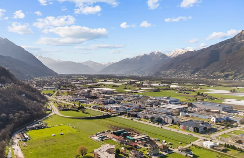 Aerial view of a town with buildings, mountains, and green fields