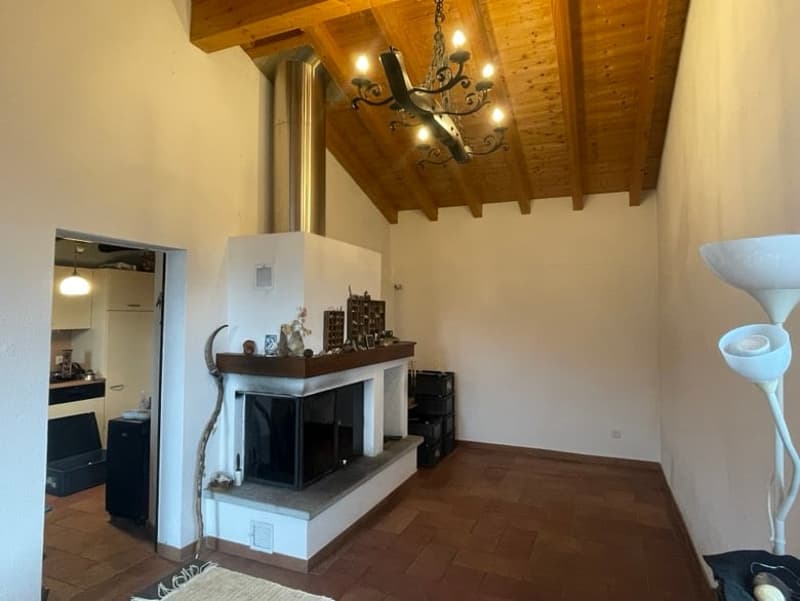 wooden ceiling, fireplace, chandelier, tiled floor, white walls, black furniture